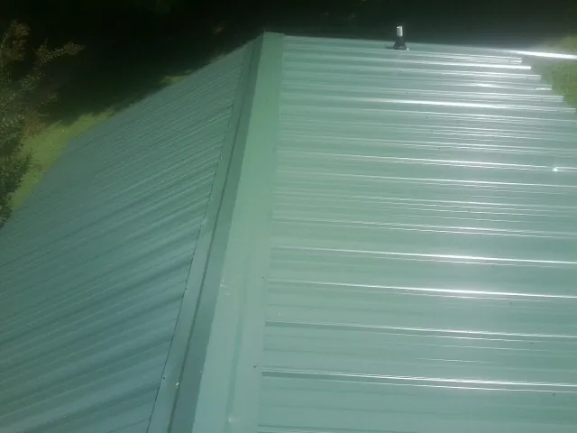 New green metal panels meeting at the ridge of a roof — Flat Roof Repair work by our crew in Ten Mile