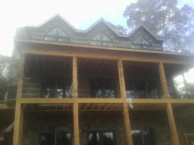 Dormers and porch framing on a large log home under construction — Roof Coating work by our crew in Ten Mile