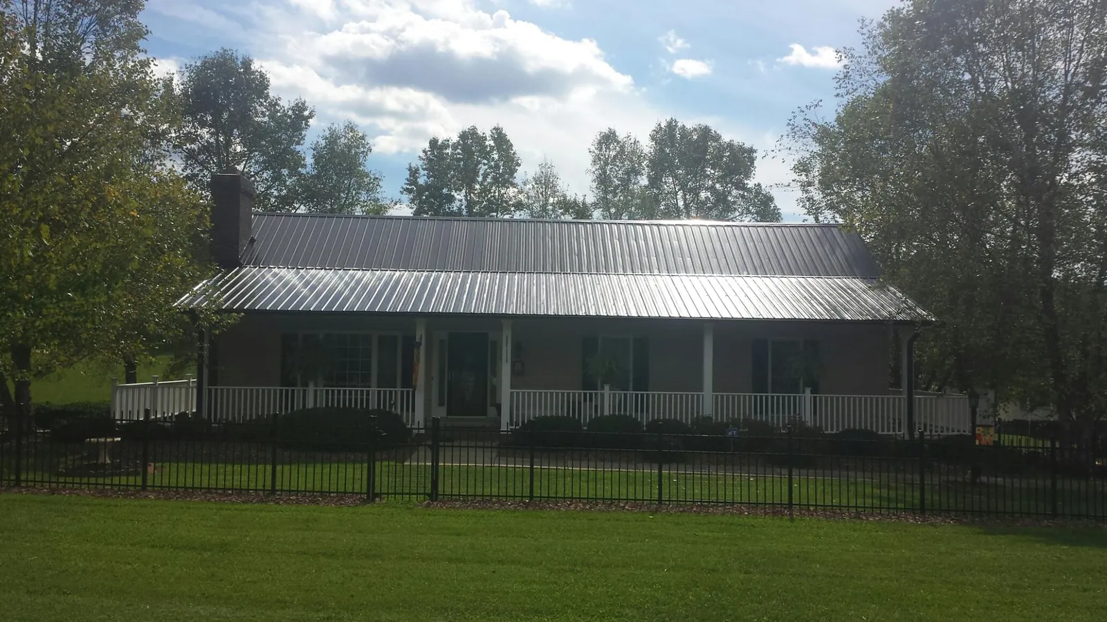 Gray metal roof on a brick ranch with a full width front porch — Gutter Guard Installation work by our crew in Ten Mile