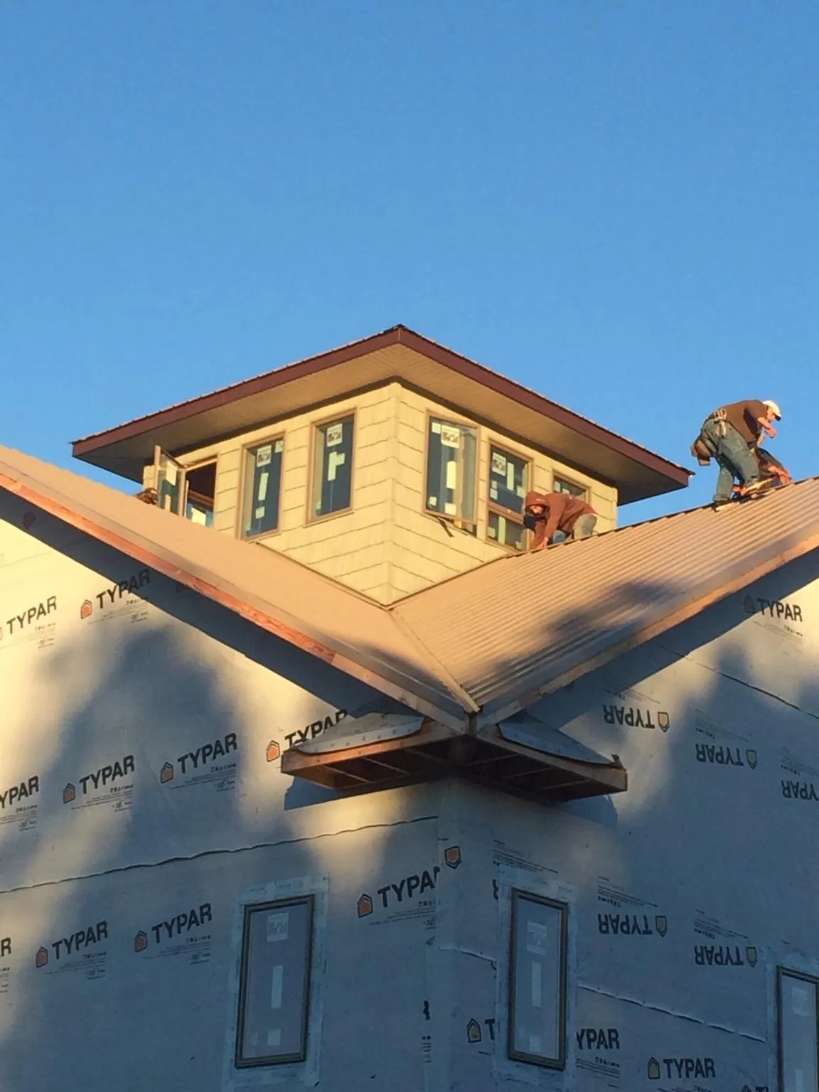 Roofers working around a rooftop cupola on a new metal roof at sunset — Roof Waterproofing in Ten Mile by Roofing Brothers